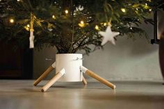 a small christmas tree in a white pot with wooden legs and stars on the top