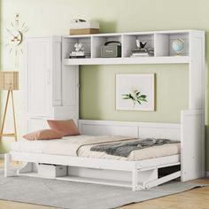 a white bed sitting under a book shelf next to a wall