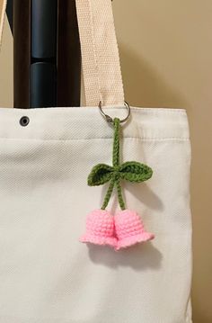 a crocheted cherry hanging from a white tote bag with a pink handle