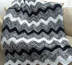 a black and white crocheted blanket sitting on top of a couch next to a pillow