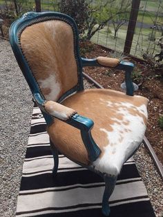 a cow hide chair sitting on top of a black and white striped rug next to a fence