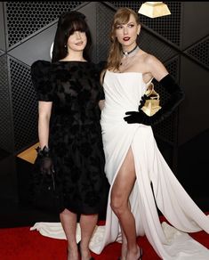 two women standing next to each other on a red carpet