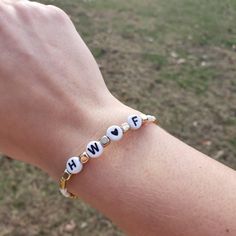 a person wearing a bracelet with the word hope written on it in white letters and gold beads