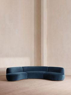 a blue couch sitting on top of a hard wood floor next to a white wall