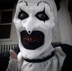 a man dressed as a clown with white makeup and black hair