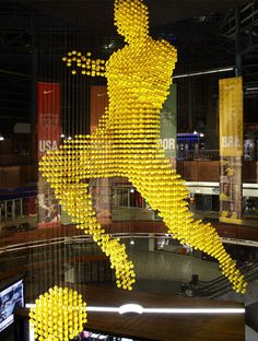 there is a sculpture made out of yellow balls in the shape of a running man