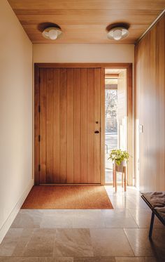 an entryway with wooden paneling and two planters on the side walk way