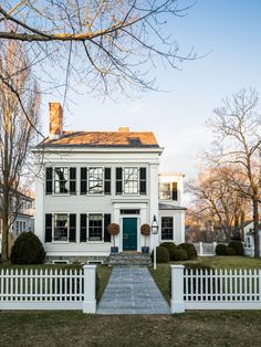 a white house with black shutters and a green door