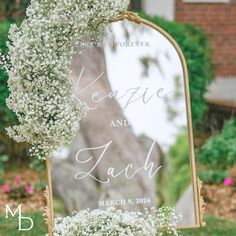 a wedding sign with baby's breath in front of a tree and flowers on it