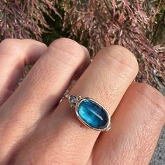 This beautiful ring features an incredible deep blue Ocean Kyanite and is accented with 2.5mm Diamonds. Set in 14k yellow gold and finished on Emily's signature band. Approx Stone Size: 13ct x 9ct Approx Ct. Weight: 4.45 ct This ring is handmade in our Hudson Valley studio. If you have questions about sizing, shipping or custom orders please reach out to us! Blue Emerald Cut Rings With Bezel Setting, Blue Emerald Cut Ring With Bezel Setting, Oval Blue Opal Ring In 14k Gold, Elegant Apatite Rings As A Gift, Elegant Apatite Rings For Gifts, Blue Oval Moonstone Ring In 14k Gold, Blue Emerald Ring With Bezel Setting, Oval Apatite Gemstone Ring, Heirloom Blue Emerald Ring