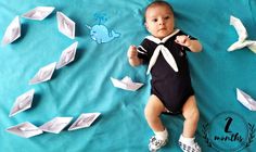 a baby laying on top of a blue blanket next to white paper birds and origami