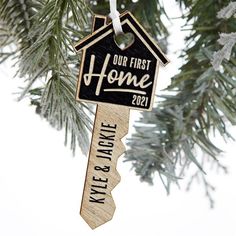 a christmas ornament hanging from a tree with the words our first home on it