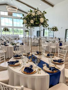 the tables are set with blue and white linens, gold chargers and place settings