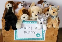 a wooden crate filled with stuffed animals and a sign that says adopt a puppy on it