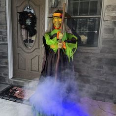 a man dressed as a witch holding a broom and standing in front of a door