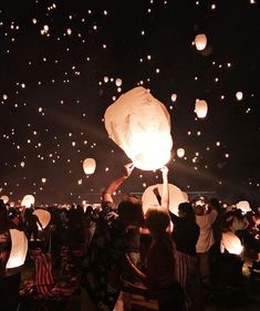 people releasing lanterns into the sky at night