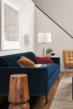 a living room filled with furniture and a stair case next to a wall mounted painting