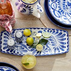 blue and white plates with lemons, limes, and cups on the table