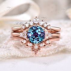 a blue diamond ring set on top of a white lace covered cloth with other jewelry items in the background