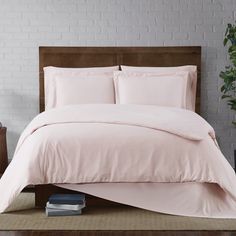 a bed with pink sheets and pillows in a room