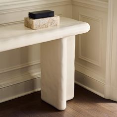 a white marble table with a black book on it's top in front of a wall