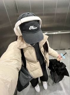 a person with a hat and coat on is holding a black bag while standing in an elevator