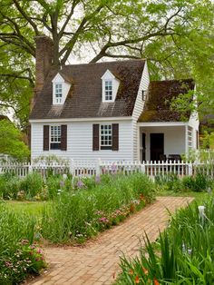 a white house surrounded by flowers and trees