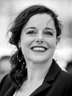 a black and white photo of a woman with big hoop earrings smiling at the camera