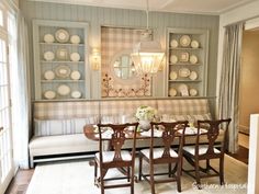 a dinning room table with chairs and plates on the wall above it, next to a couch