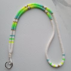 a white and green beaded lanyard with a metal hook on it's end