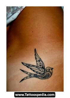 a tattoo on the back of a woman's stomach, with a bird flying over it