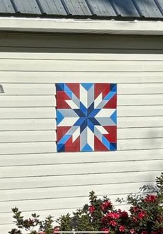 a red, white and blue quilt hanging on the side of a house