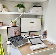 a desk with two laptops and a desktop computer on it, in front of a monitor