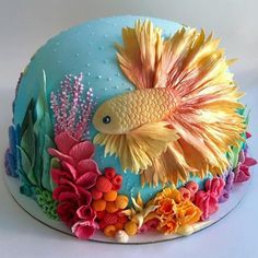 there is a blue cake decorated with goldfish and corals on the bottom layer