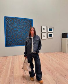 a woman standing in an art gallery holding a purse