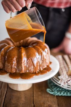 someone pouring caramel sauce on a bundt cake