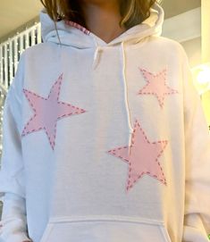 a woman wearing a white hoodie with pink stars on it