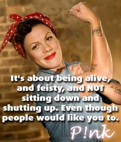 a woman with tattoos and a red bandana on her head is posing in front of a brick wall