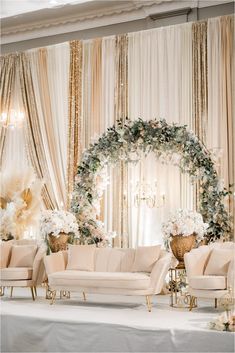 an elegant wedding setup with white flowers and greenery on the walls, couches, and chandelier