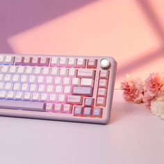 a pink and white keyboard sitting on top of a table next to some flower buds