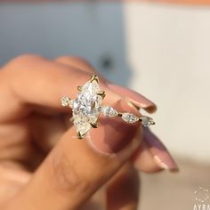 a close up of a person's hand holding an engagement ring