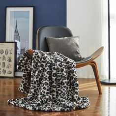 an animal print blanket sitting on top of a wooden floor next to a black chair