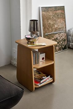 a small wooden table with books on it and a lamp next to it in the corner