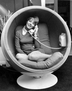 a woman sitting in a ball chair talking on the phone while holding a telephone to her ear