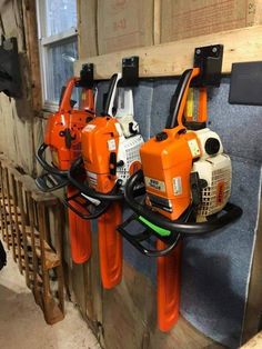 three orange chainsaws are hanging on the wall