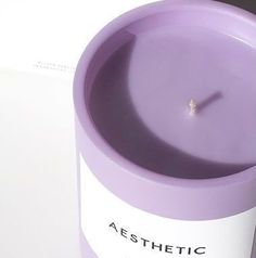 a purple candle sitting on top of a white table next to a box with the word aesthetic written on it