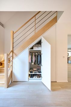 an open closet under the stairs with shoes and clothes in it, next to a staircase