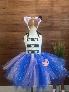 a dress made to look like a cat with blue and white tulle, on display in front of a wooden wall