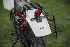 the rear end of a white motorcycle parked on grass