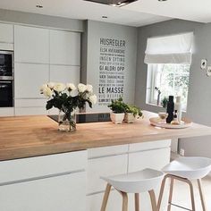 a kitchen with white cabinets and wooden counter tops next to a window filled with flowers